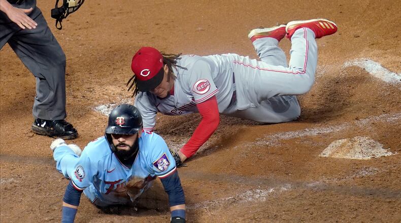 Minnesota Twins' Marwin Gonzalez, left, scores on a wild pitch by Cincinnati Reds' Luis Castillo, right, who covers the plate during the fourth inning of a baseball game Saturday, Sept. 26, 2020, in Minneapolis. The Twins won 7-3, with Castillo taking the loss. (AP Photo/Jim Mone)