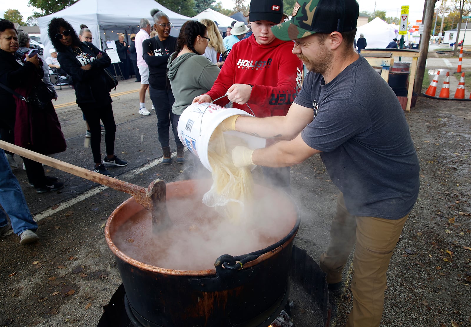 Ingredients are added to the cauldron of apple butter as it boils over a fire at the Enon Apple Butter Festival. STAFF
