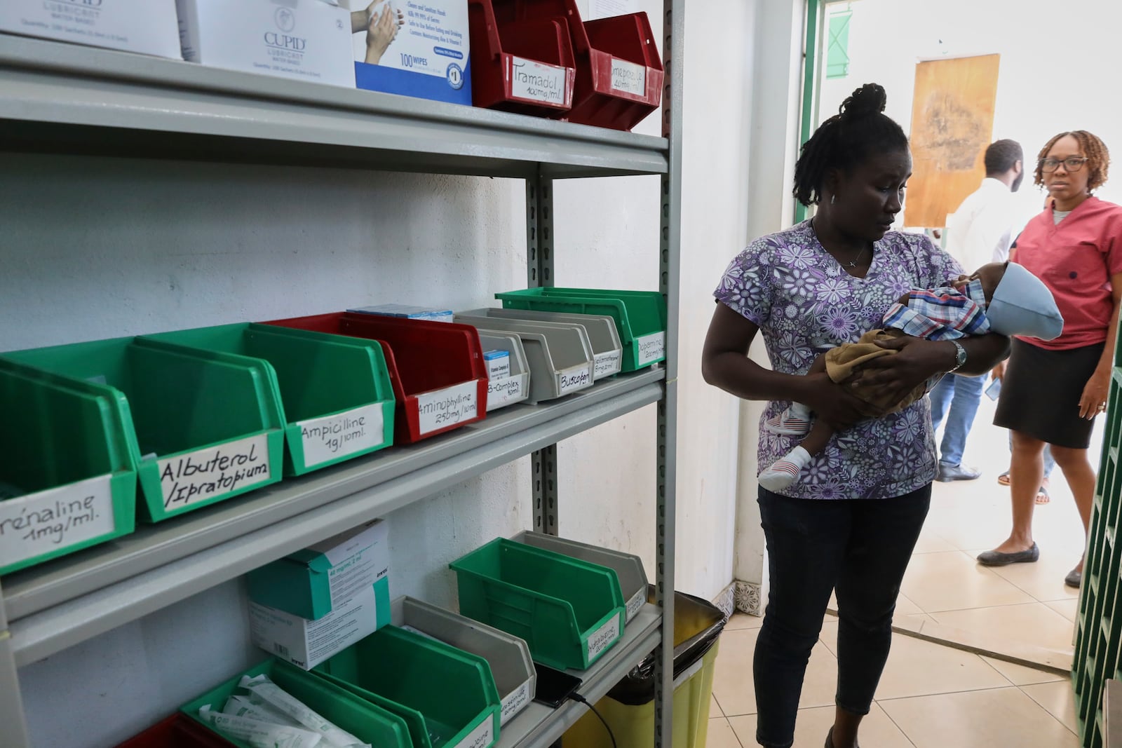 A patient cradles a baby while waiting to receive medicine at New Hope Hospital in Plaine-du-Nord, Haiti, Wednesday, May 21, 2025. (AP Photo/Patrice Noel)