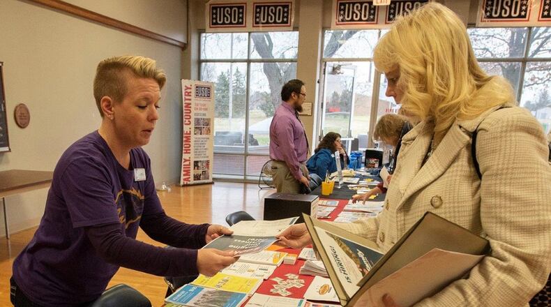 Sara Bateman, Wright-Patterson Exchange services business manager, shows a brochure to Shannon Carroll, Air Force Research Laboratory information management lead, during the ‘ThanksCIVing’ Information Fair, hosted by the Affirmative Employment Program, inside the USO Center at Wright-Patterson Air Force Base Nov. 21. Many information booths were set-up to share information about services and benefits available to Air Force civilian employees. (U.S. Air Force photos/Michelle Gigante)
