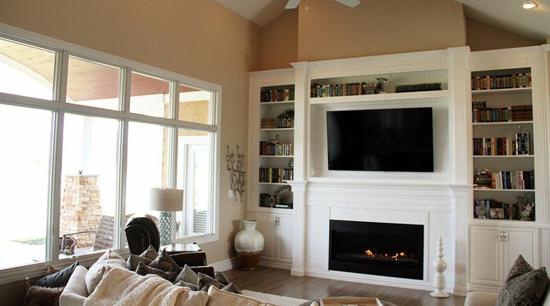 The open great room sits under a vaulted ceiling and receives abundant natural light from a row of four large windows, which add a panoramic pond view. Expansive built-ins around the fireplace offer a niche for a large-screen TV, book shelves and upper moldings.