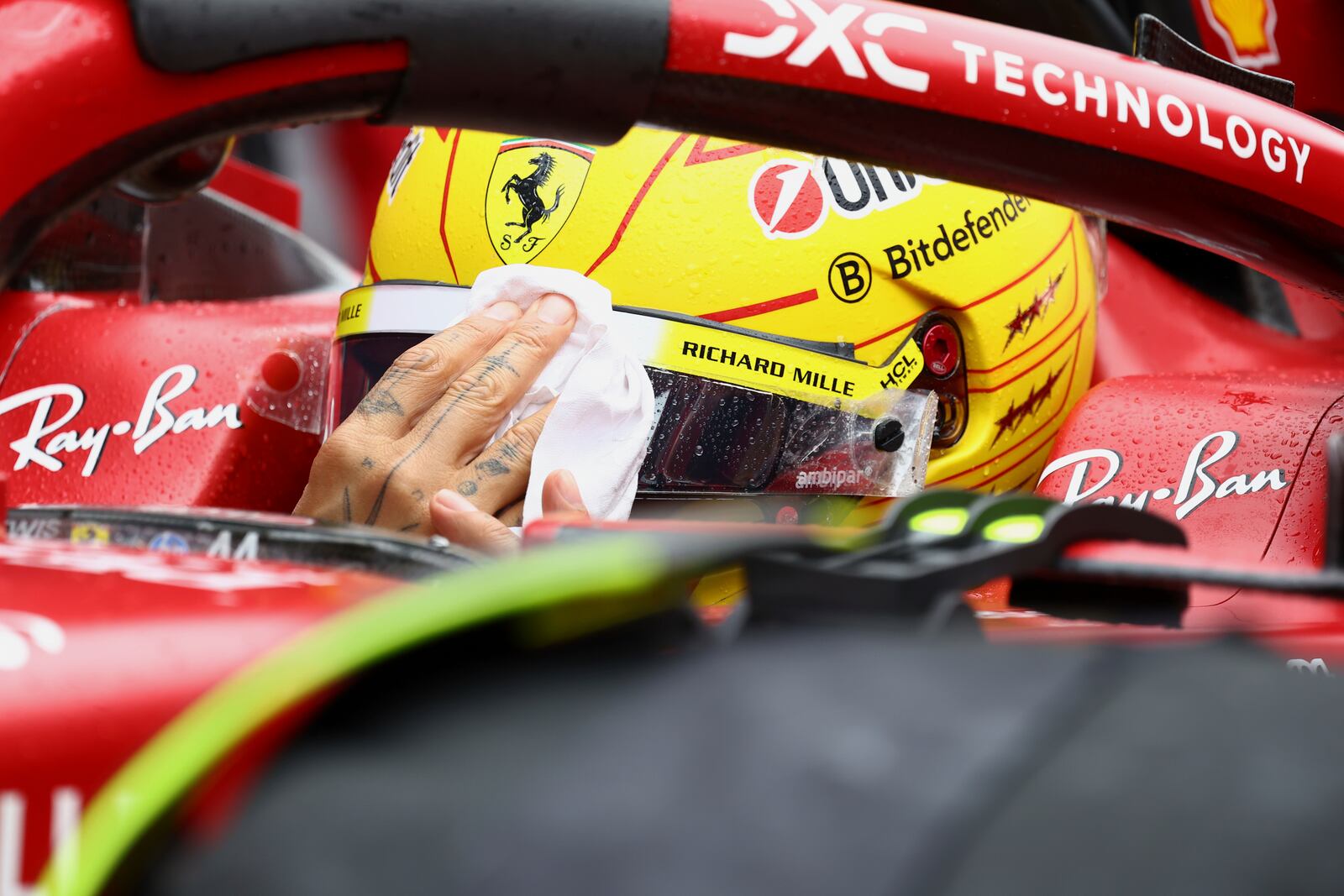 Ferrari driver Lewis Hamilton of Britain wipes rain off his face visor prior to the start of the Formula One Grand Prix at the Spa-Francorchamps racetrack in Spa, Belgium, Sunday, July 27, 2025. (Yves Herman, Pool Photo via AP)