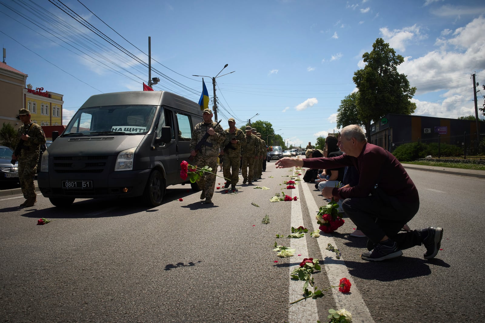 Villagers throw flowers on the road during the funeral procession of Maksym Baluyev, a soldier who was killed in battle with the Russian troops, in the village of Novi Petrivtsi close to Kyiv, Ukraine, Monday, June 23, 2025. (AP Photo/Efrem Lukatsky)