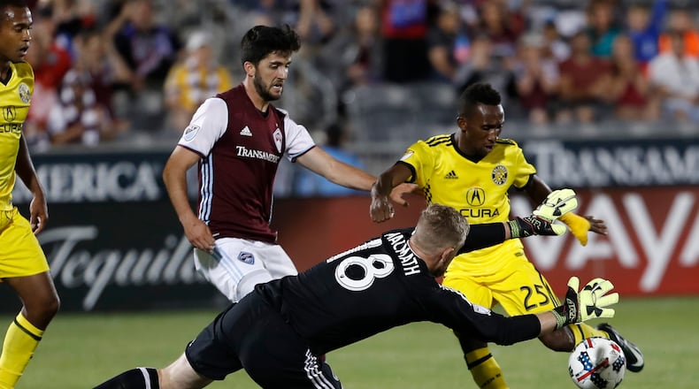 Columbus Crew defender Harrison Afful, back right, has his shot blocked by Colorado Rapids goalkeeper Zac MacMath, front, as defender Eric Miller looks on in the second half of an MLS soccer game Saturday, June 3, 2017, in Commerce City, Colo. The Rapids won 2-1. (AP Photo/David Zalubowski)