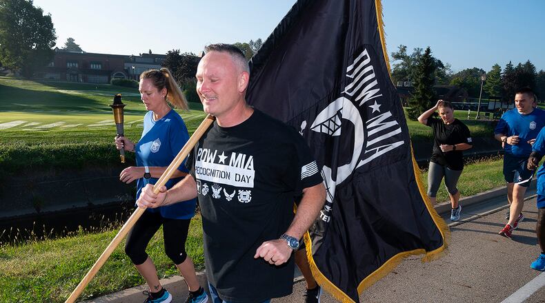 Chief Master Sgt. Shawn Plowman, 88th Diagnostics and Therapeutics Squadron, carries the POW/MIA Flag while Chief Master Sgt. Lindsey Wolf, Air Force Materiel Command command paralegal, holds up the torch as they lead a Wright-Patterson Chiefs Group delegation on the annual POW/MIA run Sept. 17. Runners delivered the torch and flag to the POW/MIA Recognition Day wreath-laying ceremony at Wright-Patterson Air Force Base. U.S. AIR FORCE PHOTO/R.J. ORIEZ