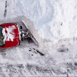 Aerial view of a snowplow clearing a snow-covered parking lot in Trenton, Ohio.
