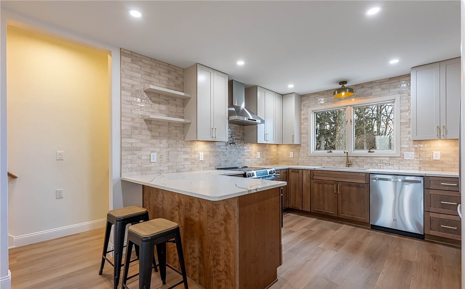 The remodeled kitchen has LVP flooring, updated wood cabinets, a breakfast bar, tile backsplash and quartz countertops. CONTRIBUTED