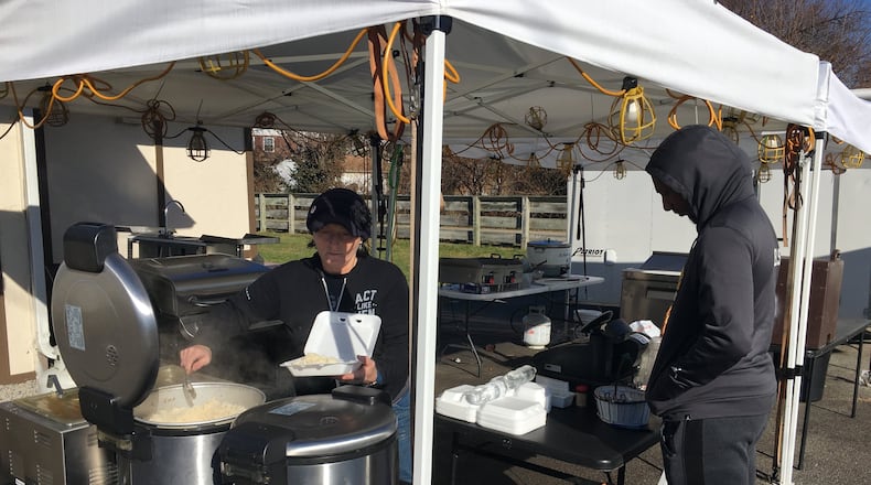 Owner Jennifer Roberts serves Austin Daniels some chicken on rice with her special sauce at Bourbon Bayou Bistro on North Detroit Street in Xenia. Roberts has been offering her cajun fare under a tent for more than two years while working to bring the building formerly occupied by Stan the Donut Man up to code. RICHARD WILSON/STAFF