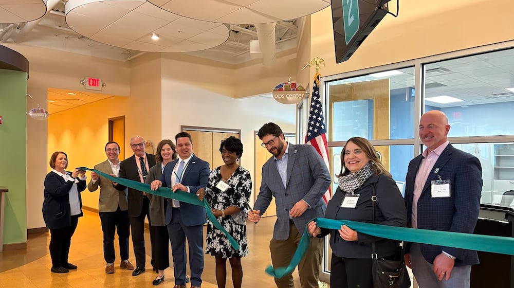 Mile Two co-founder and CEO Jeff Graley, center, cuts the ribbon with friends and colleagues at his company's new Springfield Street offices Thursday Jan. 29 in Riverside. THOMAS GNAU/STAFF