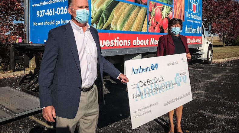 The Foodbank of Dayton unveiled its new refrigerated truck during a mobile food pantry Oct. 8, 2020, in New Lebanon. Anthem Blue Cross and Blue Shield donated the truck. From left, is Rob Cleary, regional VP Anthem of Ohio and Michelle Riley, CEO of The Foodbank Inc. who announced the collaboration. JIM NOELKER/STAFF