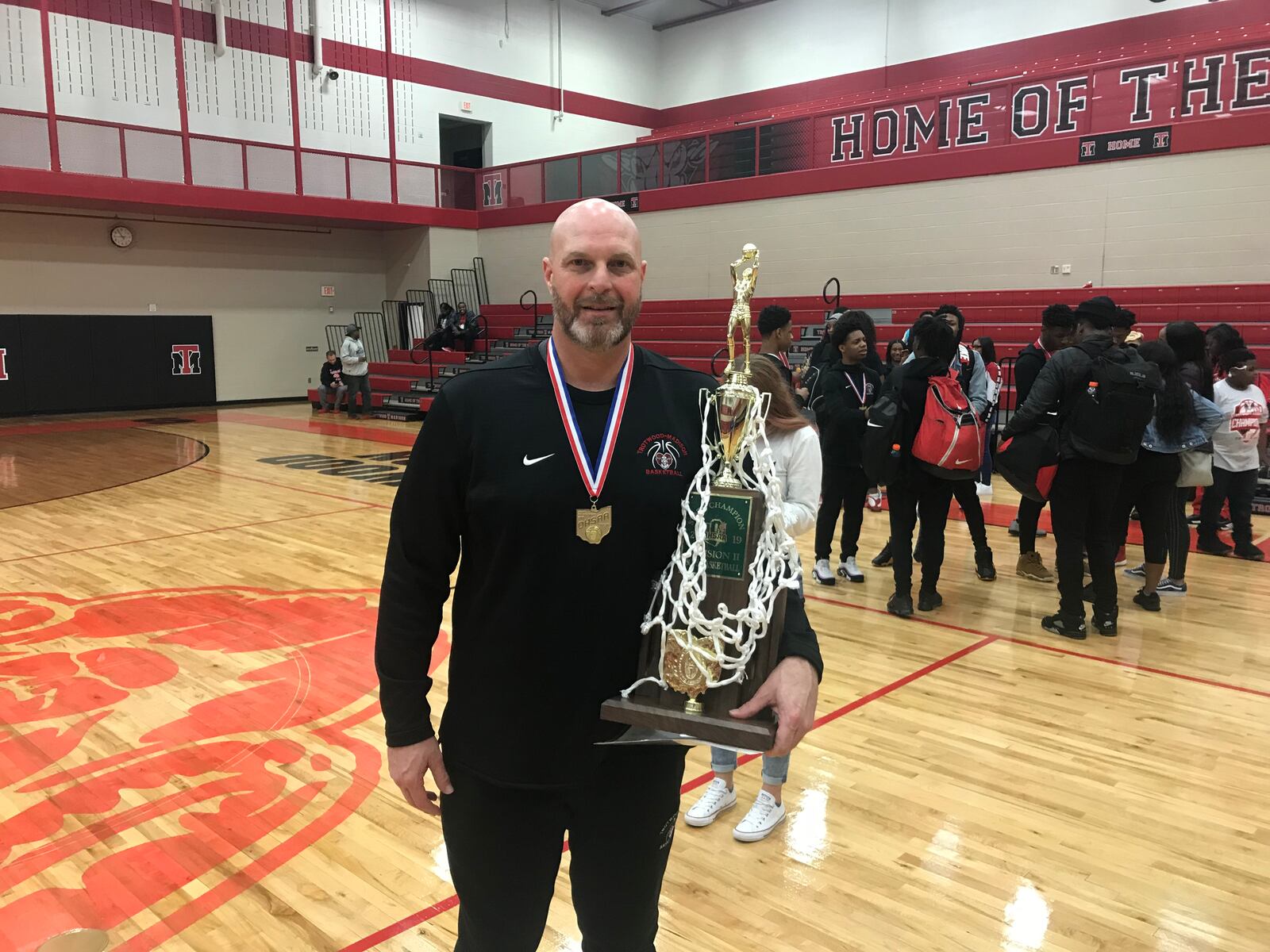 Coach Rocky Rockhold holds the trophy and net following a celebration Saturday evening at the Trotwood-Madison High School gymnasium in honor of the Rams' first basketball state championship.