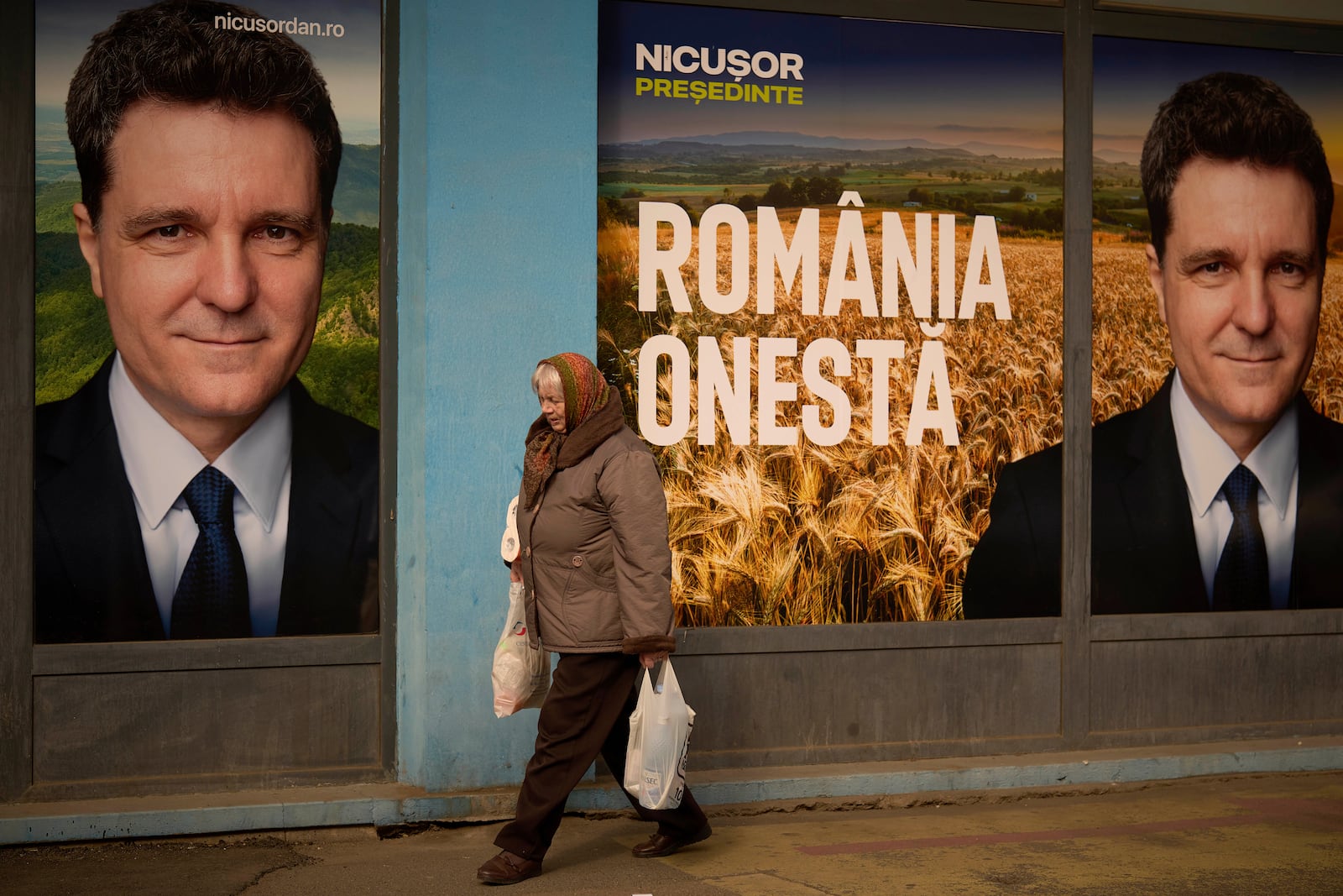 A woman walks by posters of Nicusor Dan, the mayor of Bucharest and presidential candidate in the upcoming May elections in Bucharest, Romania, Friday, March 28, 2025. (AP Photo/Vadim Ghirda)