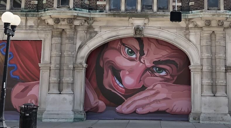 Look who stirs: Vinyl posters of a 40-foot sleeping giant on the north side of the Dayton Arcade were replaced Friday, a day after the developer closed on a $90 million effort to revive the complex. The new posters show a giant whose eyes are very much open and who has a big grin on his face. If things go according to plan, the arcade could reopen in 2020. CORNELIUS FROLIK / STAFF