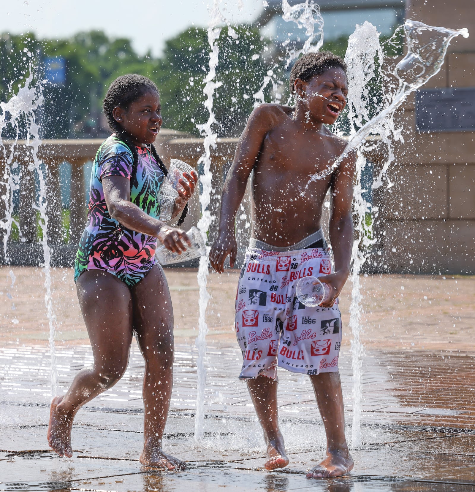 Gahn-Maria Favors (left) throws water from a cup on to Nor'ryan Shropshire at the splash pad at RiverScape Metropark on Tuesday, June 22. The splash pad was full of families on Tuesday evening, with the area still under a heat advisory. The heat advisory is scheduled to last until Wednesday evening. BRYANT BILLING / STAFF