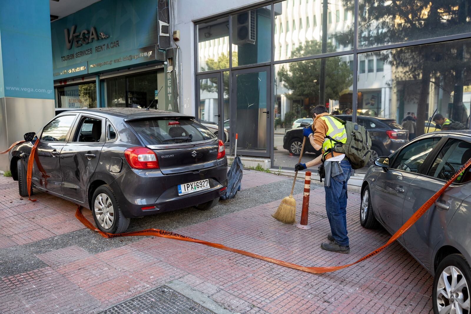 A municipal worker cleans the area outside Hellenic Train headquarters, Greece's main railway company, following a bomb explosion Friday night causing causing limited damage but no injuries, in Athens, Greece, on Saturday, April 12, 2025. (AP Photo/Yorgos Karahalis)