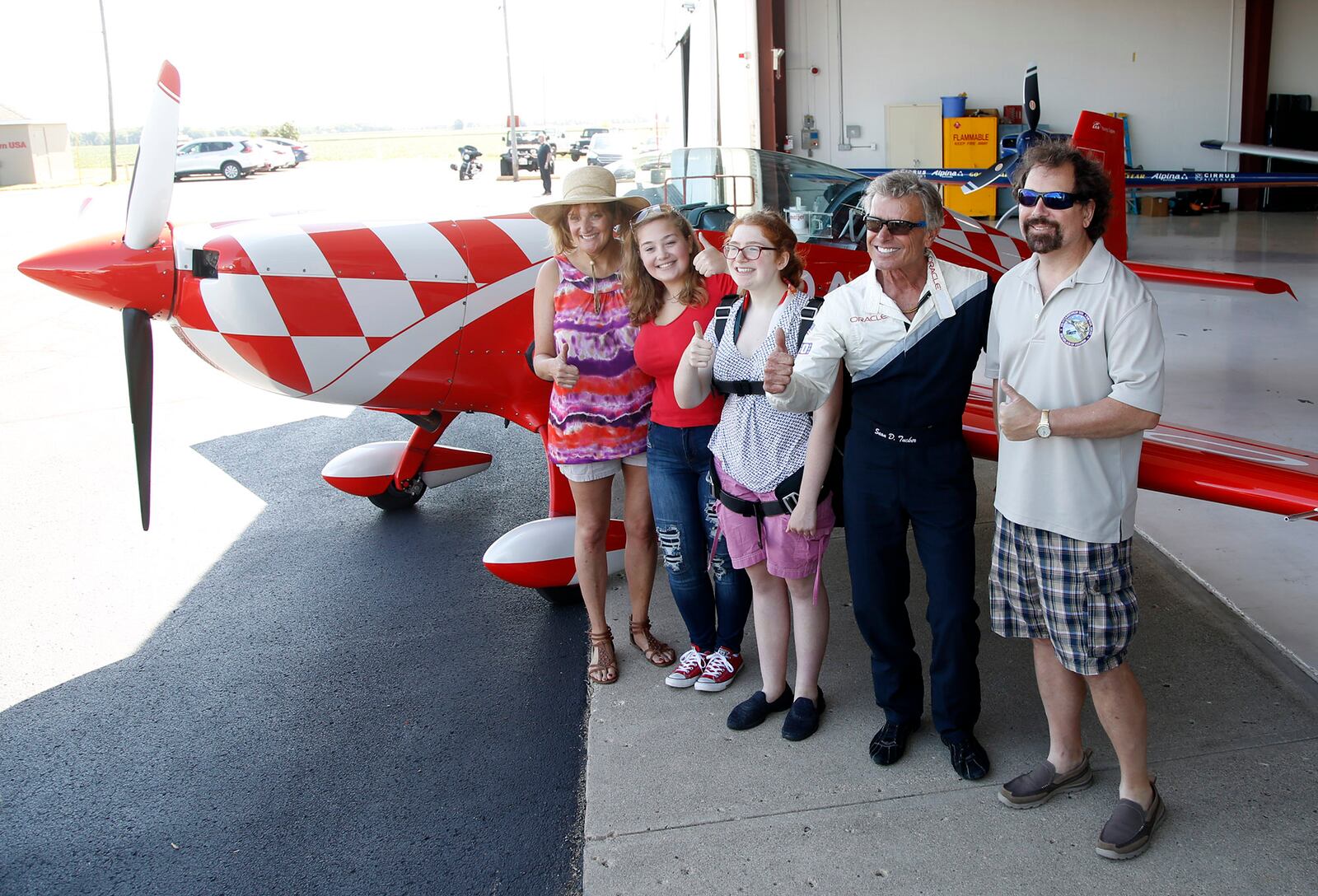 Dayton Air Show Young Eagles essay contest winner Kayla Hughes, 14, center, with her family and legendary pilot Sean D. Tucker at the Piqua Airport.  Hughes' originally scheduled flight was cancelled due to poor weather days before the Dayton Air Show in June but Tucker found a way to make it happen on Tuesday in Piqua.   TY GREENLEES / STAFF