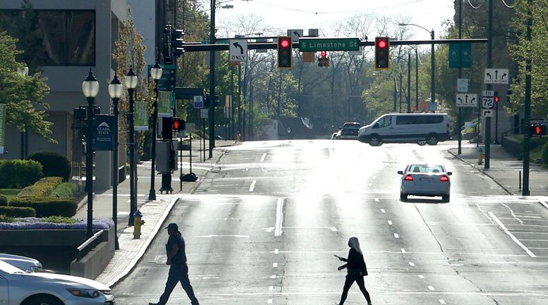 A man and woman are silhouetted as they cross High Street while it glows in the early morning sun. BILL LACKEY/STAFF