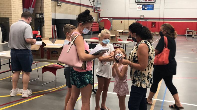 Troy schools K-6 curriculum director Danielle Romine (right) talks to kindergartner Raelynn Clark about starting school as families pick up Chromebook computers for online learning Wednesday, Sept. 2, 2020 at Troy High School.