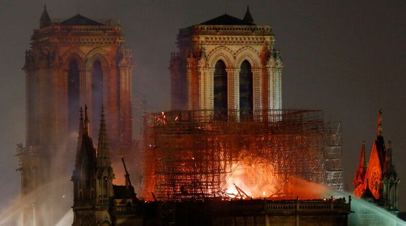 FILE - In this April 15 2019, file photo, flames illuminate the night sky as Notre Dame Cathedral burns in Paris. The cathedral stands crippled, locked in a dangerous web of twisted metal scaffolding one year after a cataclysmic fire gutted its interior, toppled its famous spire and horrified the world.