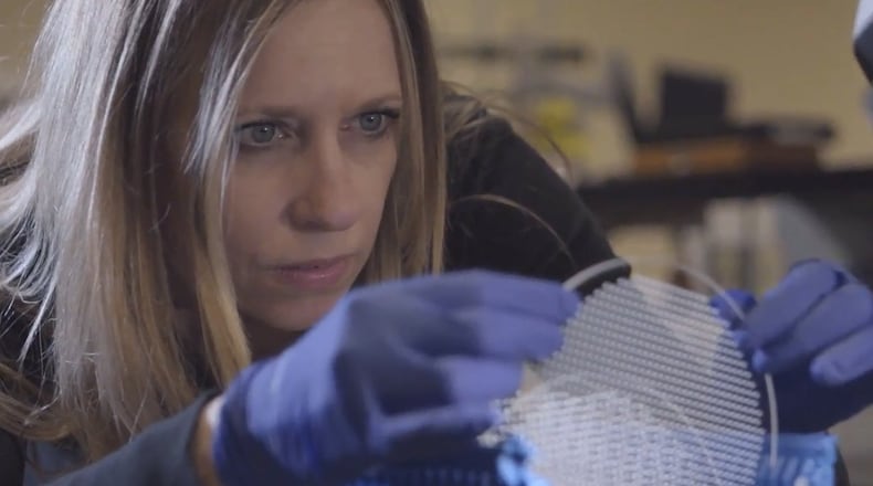 Bullen Ultrasonics employee Robin Brown inspects a MEMS glass wafer, a key component in the production of ventilators.”