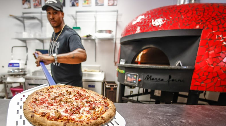 ILLY'S Fire Pizza owner, Robert Gunn pulls out a fresh pizza from the oven. JIM NOELKER/STAFF