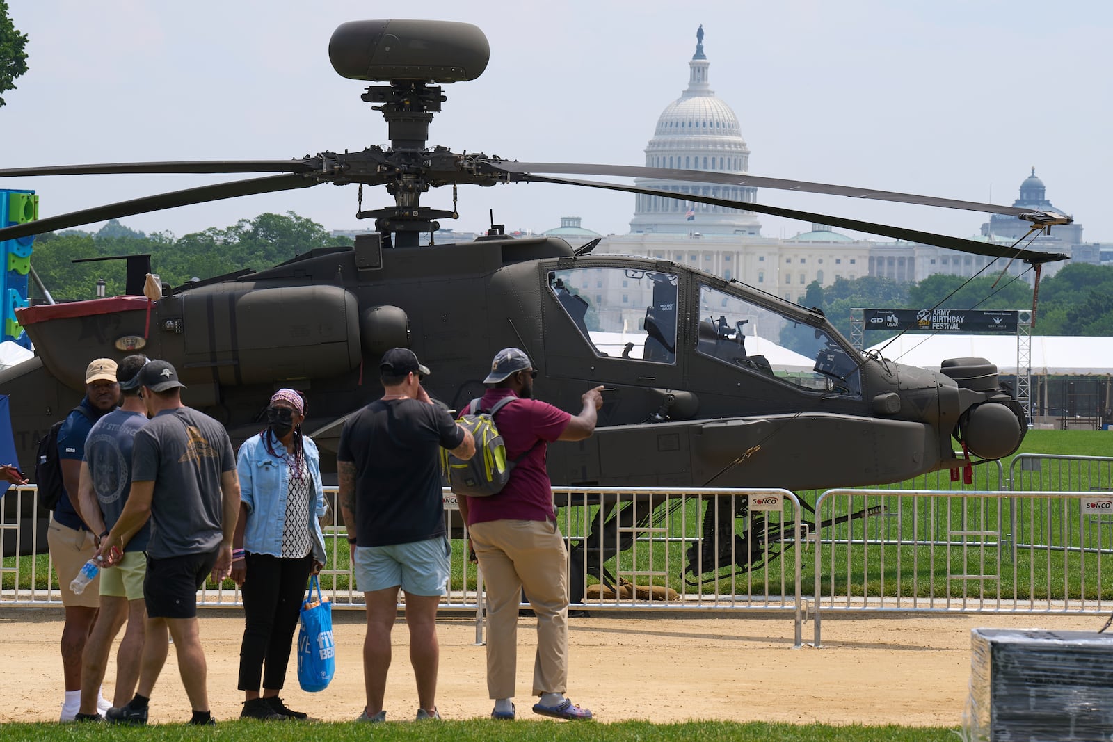 People look at a military helicopter with the Capitol in the background, Friday, June 13, 2025, on the National Mall in Washington, during preparations for an upcoming military parade commemorating the Army's 250th anniversary and coinciding with President Donald Trump's 79th birthday. (AP Photo/Jacquelyn Martin)