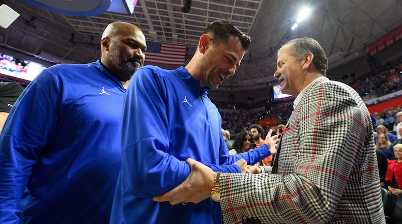 Florida head coach Todd Golden, center, shakes hands with Arkansas head coach John Calipari, right, before an NCAA college basketball game, Saturday, Feb. 28, 2026, in Gainesville, Fla. (AP Photo/Noah Lantor)