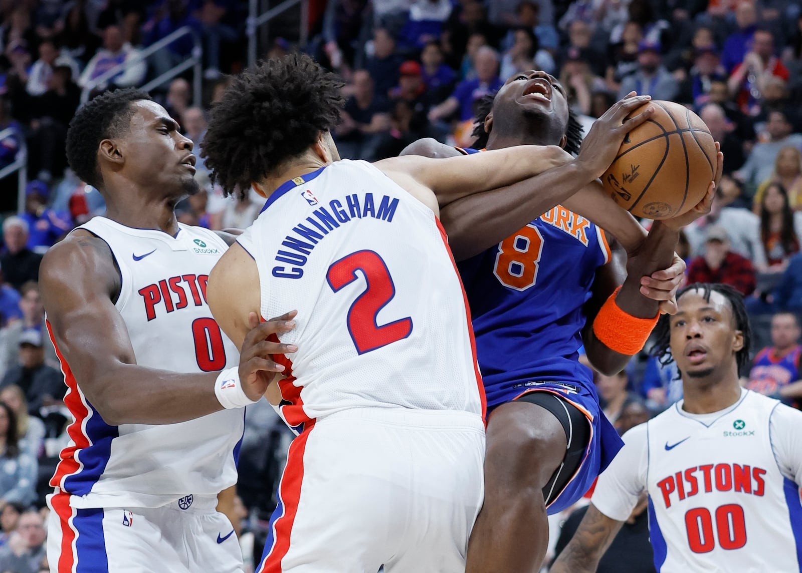 New York Knicks forward OG Anunoby (8) is fouled by Detroit Pistons guard Cade Cunningham (2) while going to the basket with Pistons' Jalen Duren (0) also defending during the first half of Game 4 of an NBA basketball first-round playoff series Sunday, April 27, 2025, in Detroit. (AP Photo/Duane Burleson)