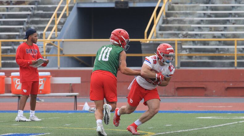 Dayton's Jack Cook hands off to Jake Chisholm at the first practice of the season on Monday, Aug. 9, 2021, in Dayton. David Jablonski/Staff