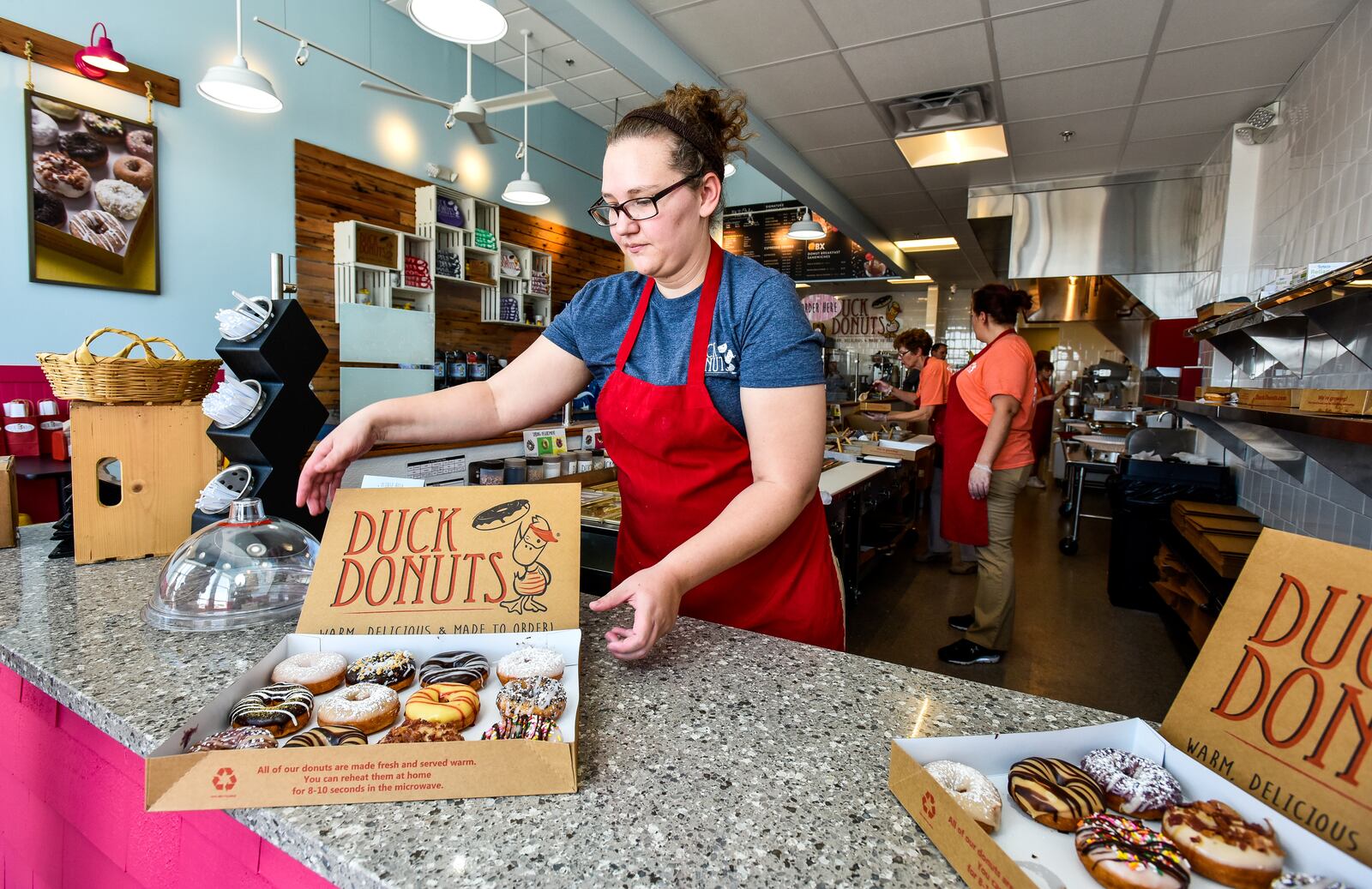Manager Jennifer Adkins places donuts for display at Duck Donuts as they opened their doors for a preview event Thursday, April 12. Duck Donuts opens April 13 in Deerfield Towne Center in Mason. The donut shop offers fresh made-to-order donuts with a variety of toppings. NICK GRAHAM/STAFF