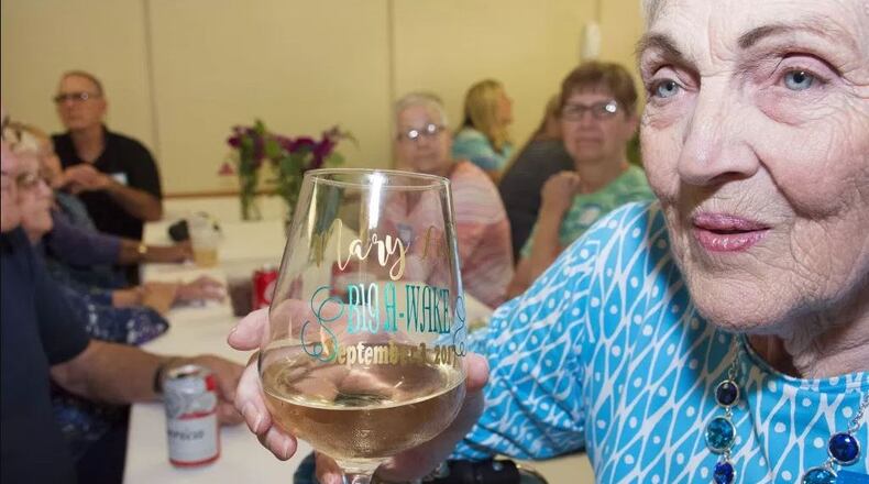 Mary Lou Spangler shows off her customized wine glass reading "Mary Lou’s Big A-Wake" with the date. Photo: Ohio's Hospice of Dayton.