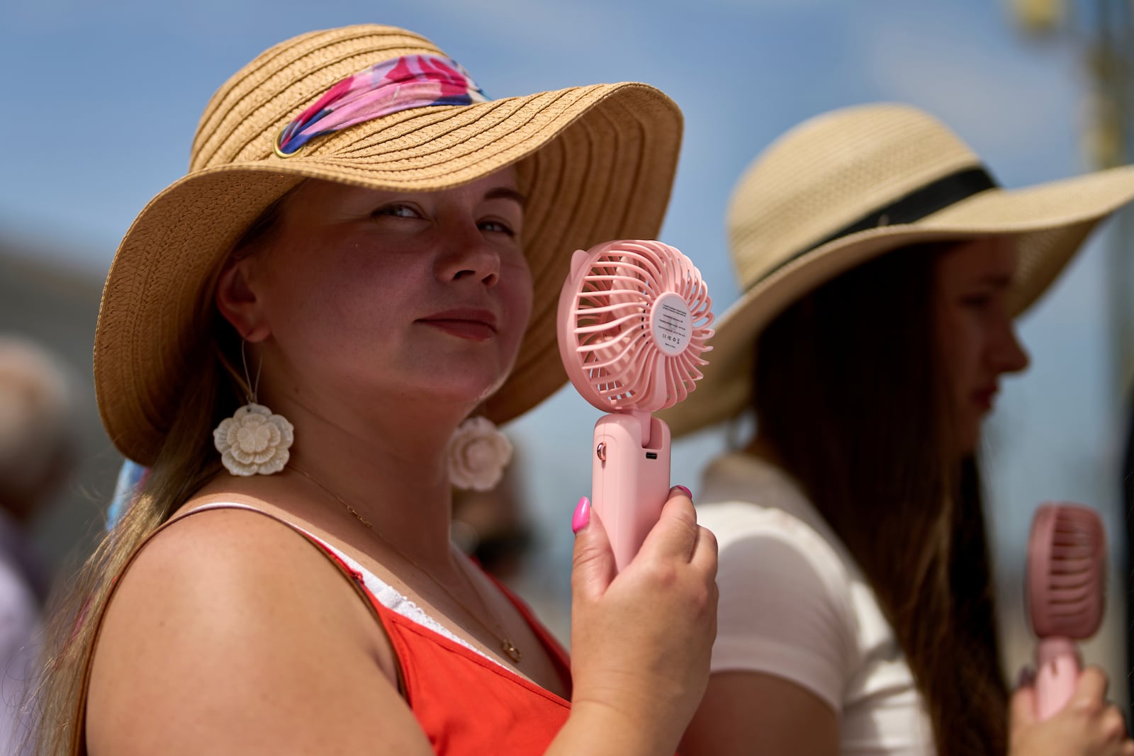 A woman cools herself with a handheld electric fan during a heat wave in Madrid, Spain, Tuesday, July 1, 2025. (AP Photo/Manu Fernandez)
