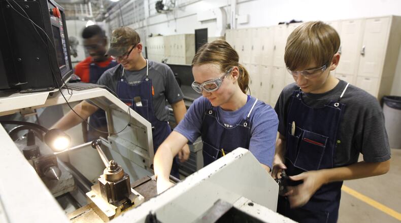 Miami Valley Career Technology Center precision machining students set up a CNC lathe for project work in September 2018. These senior class members are training for machinist jobs that are in high demand in the region. From left to right are William Stephens, Tyler Pleiman, Sarah Virag and Troy Wolfe. TY GREENLEES / STAFF