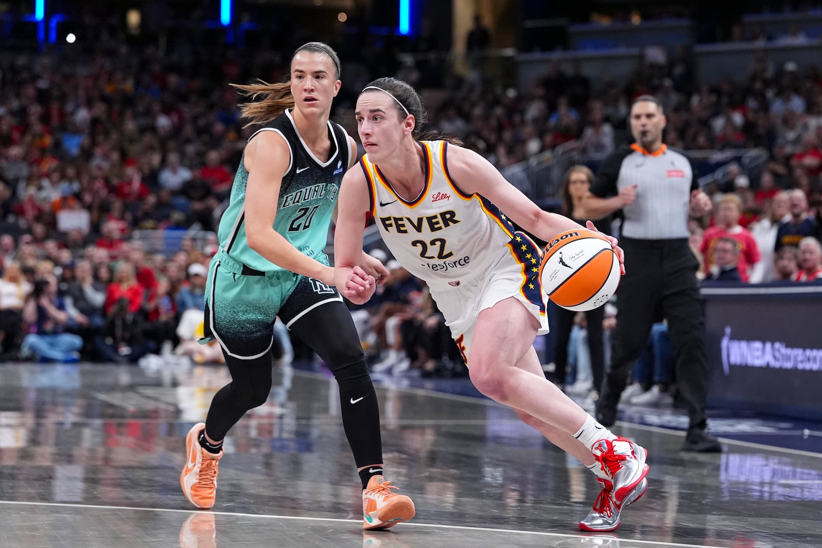 Indiana Fever guard Caitlin Clark (22) drives on New York Liberty guard Sabrina Ionescu (20) in the second half of a WNBA basketball game in Indianapolis, Saturday, May 24, 2025. (AP Photo/Michael Conroy)