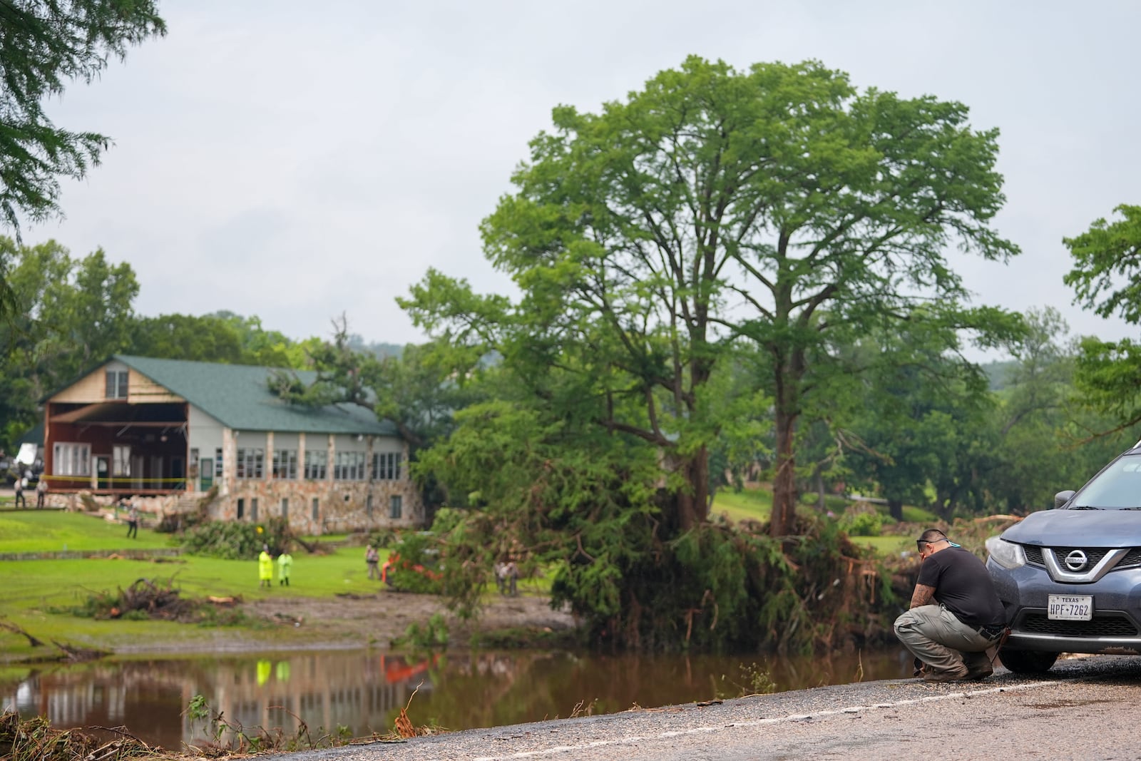 Avi Santos, 23, of San Antonio, Texas, reacts while stopping on the road alongside at Camp Mystic along the banks of the Guadalupe River after a flash flood swept through the area Sunday, July 6, 2025, in Hunt, Texas. (AP Photo/Julio Cortez)
