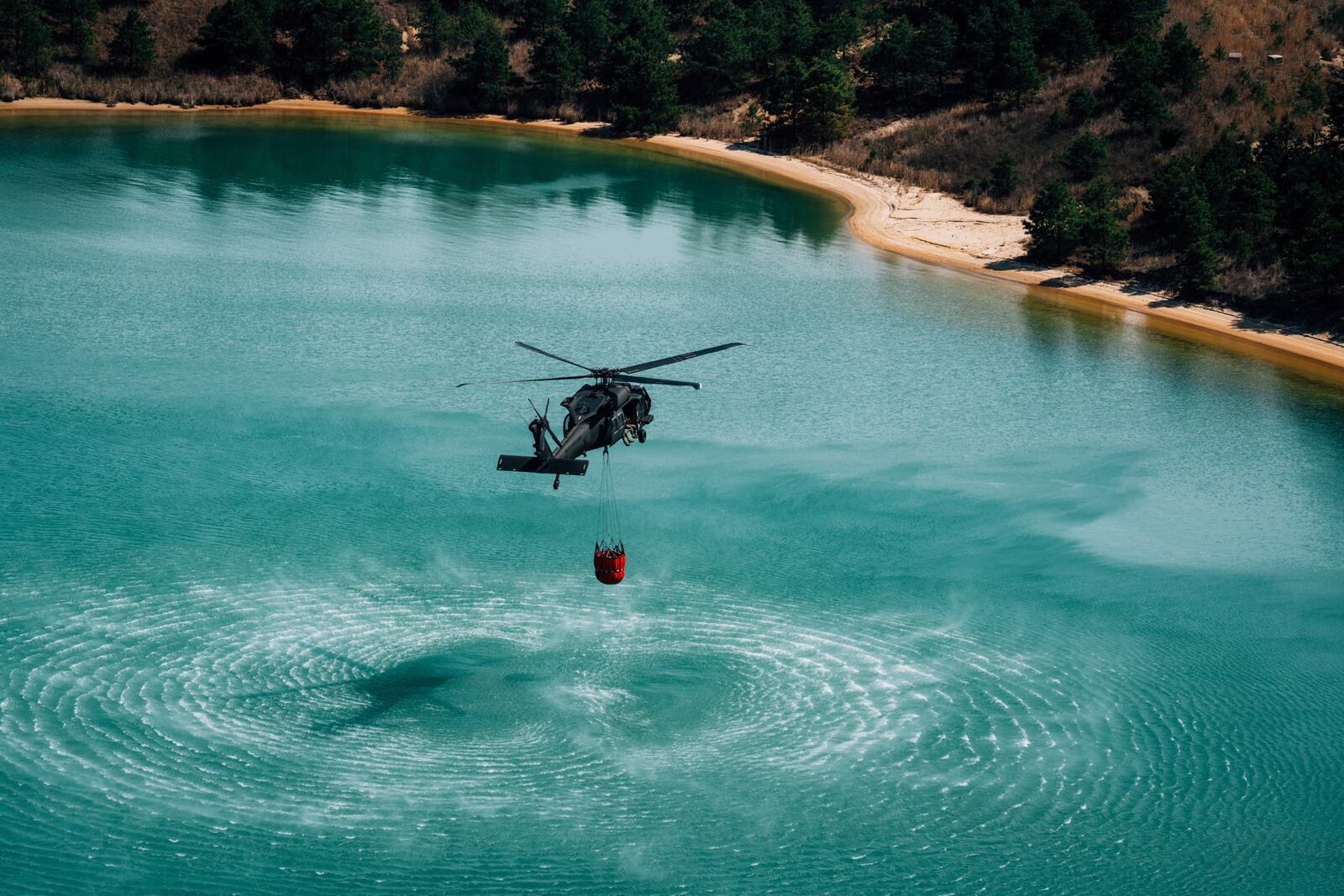 A helicopter picks up water to help battle a wildfire in Ocean County, N.J. on Thursday, April 24, 2025. (New Jersey Department of Environmental Protection via AP)