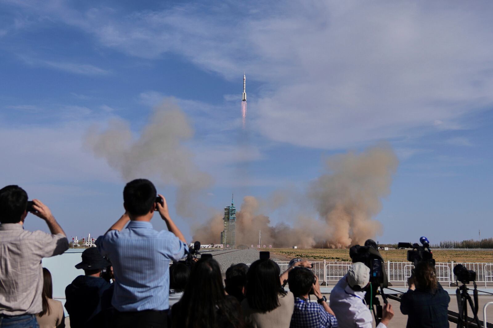 Journalists film China's Long March 2F rocket, carrying three astronauts for the Shenzhou 20 manned space mission, lifts off for a space station, at the Jiuquan Satellite Launch Center in Jiuquan, northwestern China, Thursday, April 24, 2025. (AP Photo/Andy Wong)