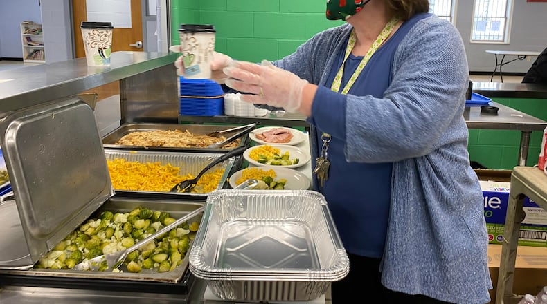 House of Bread Executive Director Melodie Bennett helps prepare a meal Friday, Dec. 25, 2020. Approximately 300 people a day get lunch from the Dayton  organization, which has founded in 1983 and has provided a lunch to the area's homeless and hungry 365 days a year since 2010. ERIC SCHWARTZBERG/STAFF