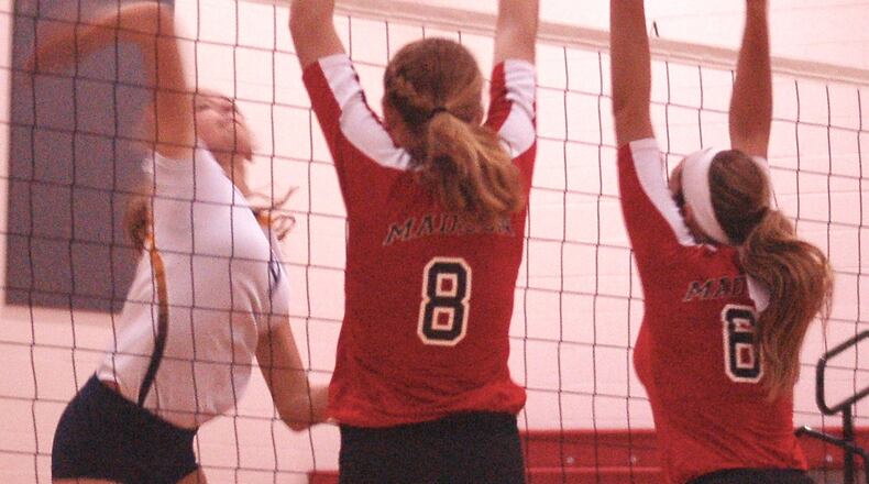 Monroe’s Kayla Foote eyes the ball on a kill attempt as Madison’s Ally King (8) and Sy Beachler (6) go up for a block during Saturday’s match at Madison. CONTRIBUTED PHOTO BY JOHN CUMMINGS