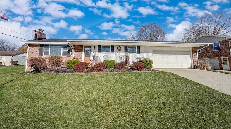 The front of the home features a concrete driveway, two-car attached garage, fully covered walkway leading to entryway and brick and vinyl siding. Contributed photo