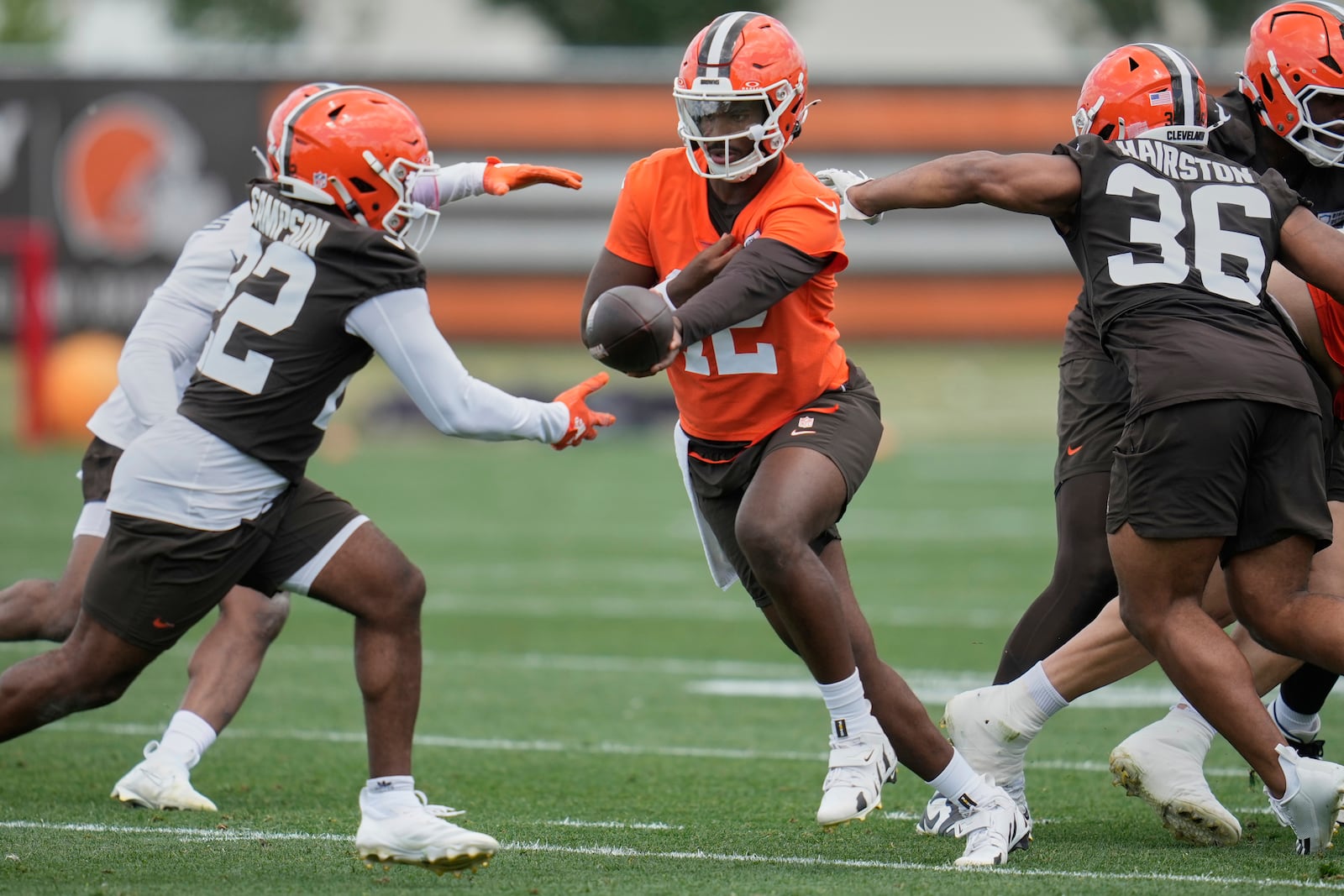 Cleveland Browns quarterback Shedeur Sanders, center, hands off to running back Dylan Sampson, left, at NFL football minicamp in Berea, Ohio, Tuesday, June 10, 2025. (AP Photo/Sue Ogrocki)