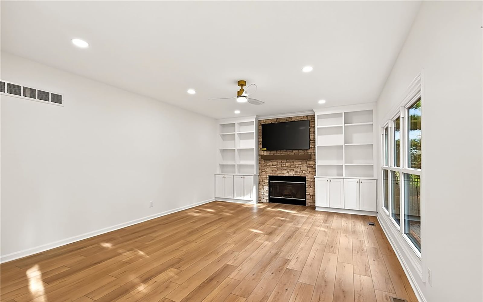 The family room has hardwood floors, a stacked stone fireplace with wood mantel and two built in bookcases with cabinets. An exterior door opens to the back patio. CONTRIBUTED