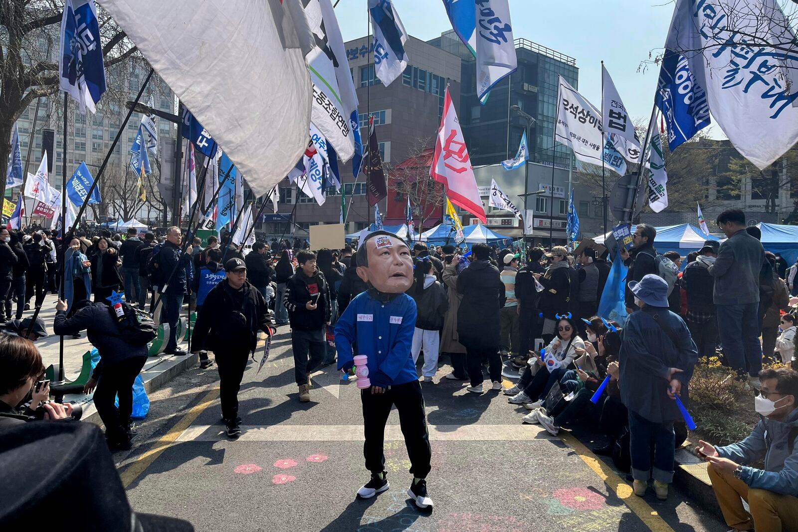 A man wearing a mask of President Yoon Suk Yeol celebrates along with others after Yoon was removed from office, near royal palace in downtown Seoul, South Korea, Friday, April 4, 2025. (AP Photo/Foster Klug)
