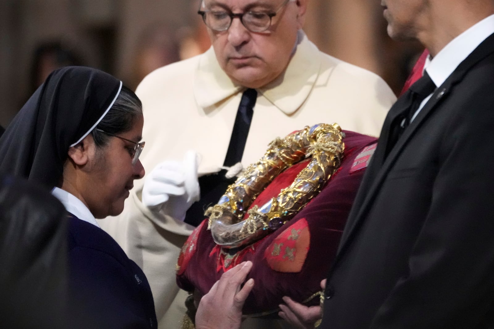 A nun touches the ancient relic that many Christians revere as Jesus Christ's "Crown of Thorns" during a ceremony to mark Good Friday at Notre Dame cathedral, Friday, April 18, 2025 in Paris. (AP Photo/Michel Euler)