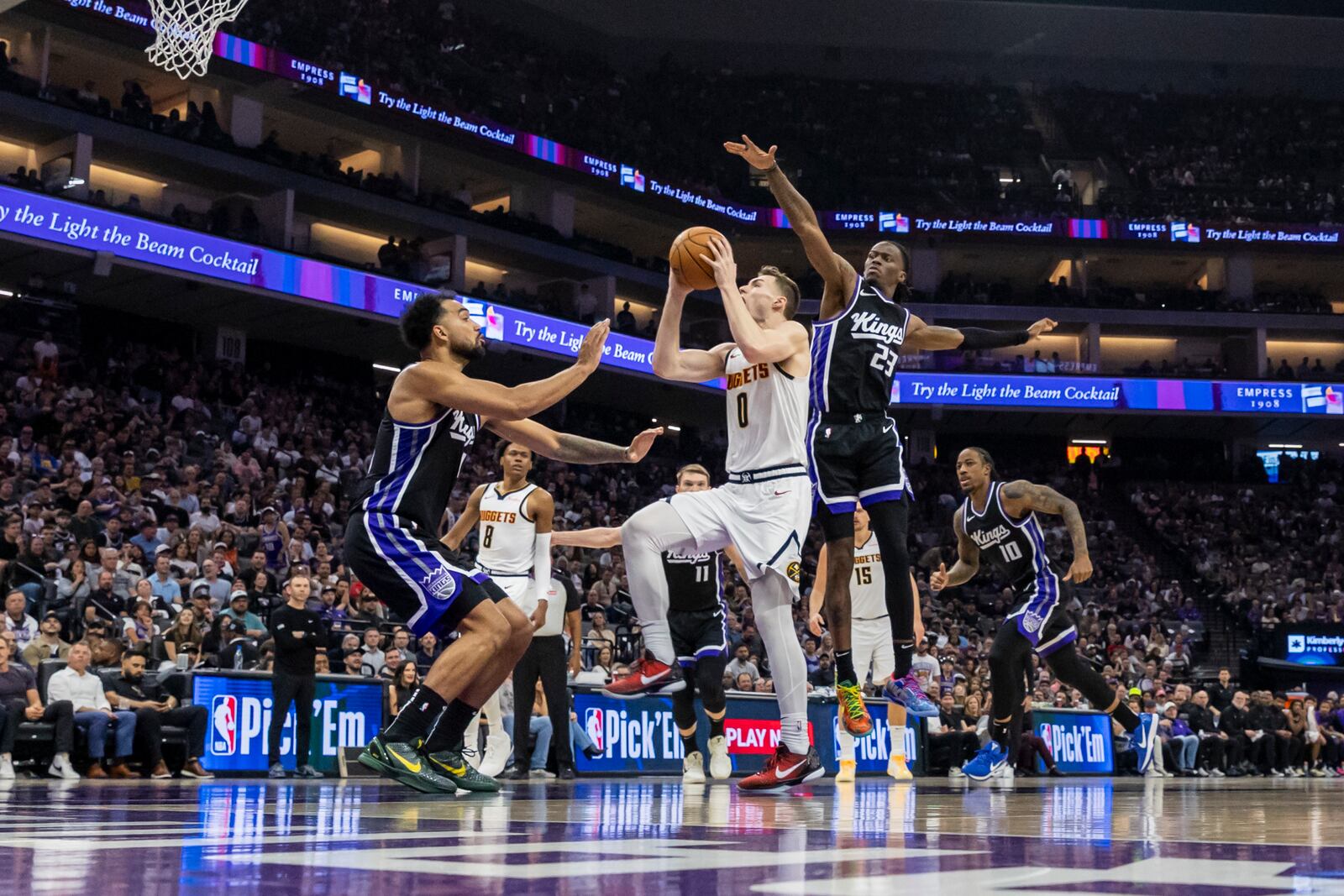 Denver Nuggets guard Christian Braun (0) goes up for a layup as Sacramento Kings forward Trey Lyles, left, defends during the first half of an NBA basketball game Wednesday, April 9, 2025, in Sacramento, Calif. (AP Photo/Sara Nevis)