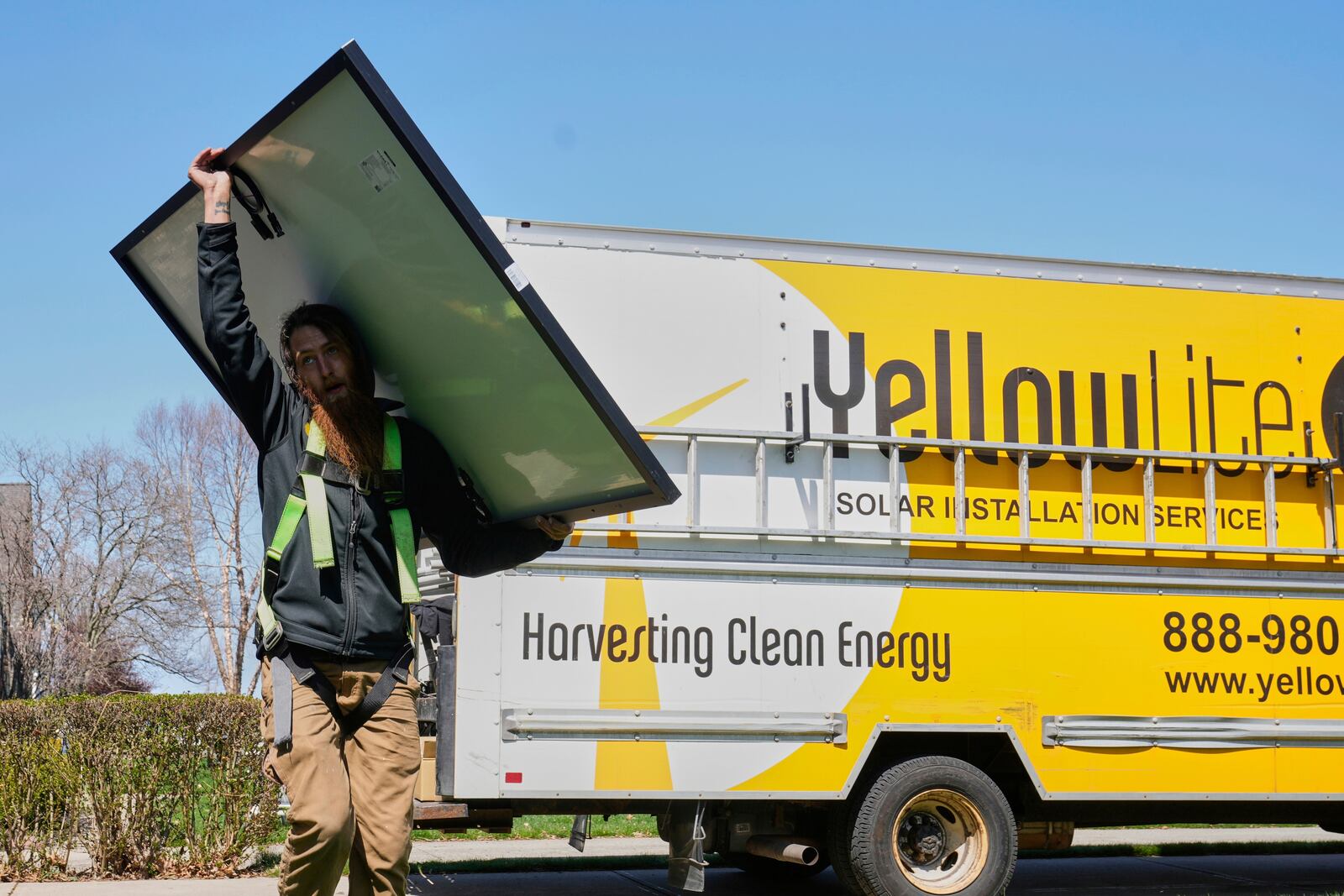 Theodore Tanczuk, of solar installer YellowLite, carries a panel from his truck to the roof of a home in Lakewood, Ohio, Wednesday, April 16, 2025. (AP Photo/Sue Ogrocki)