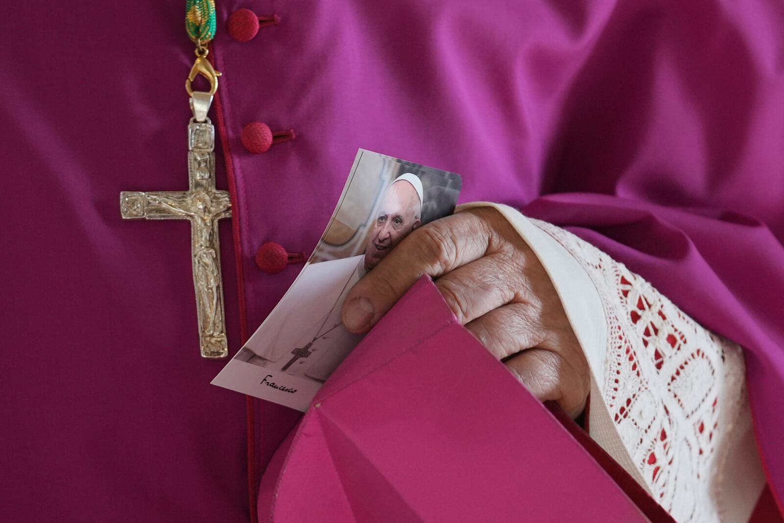 A prelate holds a picture of Pope Francis as he enters the atrium of St. Peter's Basilica at the Vatican, Wednesday, April 23, 2025, where the body of Pope Francis will lie in state for three days. (AP Photo/Andrew Medichini, Pool)