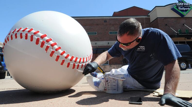 City of Dayton employee Craig Howard touches up the paint on the giant baseballs outside of Day Air Ballpark on Monday, April 10, 2023, in preparation for the Dragons' home opener. MARSHALL GORBY\STAFF