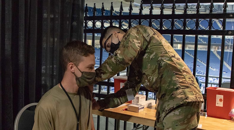 Senior Airman Dominic Patel of the 88th Health Care Operations Squadron rehearses the vaccination procedure March 22 with Airman 1st Class Andrew Trempus (seated) in the community vaccination center at Ford Field in Detroit. Both Airmen are currently assigned to the 1st Detachment, 64th Air Expeditionary Group. U.S. ARMY PHOTO/SPC. ANDREW WALSH, 5TH MOBILE PUBLIC AFFAIRS DETACHMENT