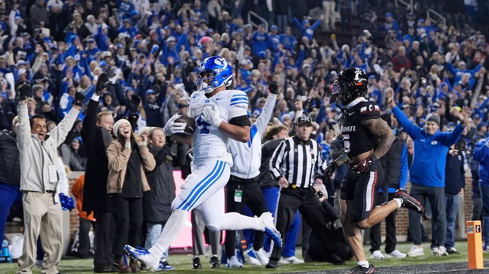 BYU running back LJ Martin (4) scores a touch down past Cincinnati safety Christian Harrison (5) during the second half of an NCAA college football game, Saturday, Nov. 22, 2025, in Cincinnati. (AP Photo/Carolyn Kaster)